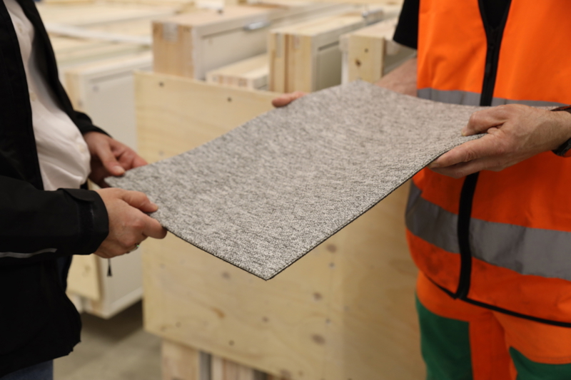 Två personer håller en mattbit mellan sig och känner på kvaliteten. De står i Ragn-Sells Reboost (återbrukshubb)