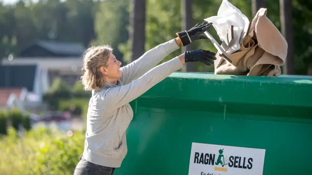 En kvinna som slänger avfall i en grön container